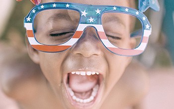 Little boy laughing with American flag glasses