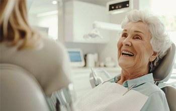 Smiling senior dental patient talking with dental team member